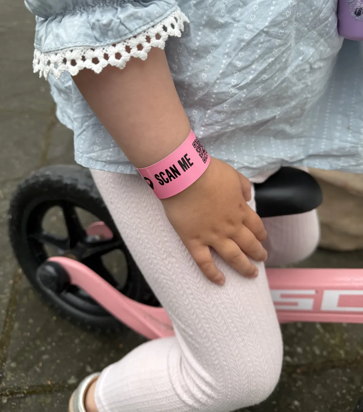 Child wearing pink AYA wristband riding bicycle